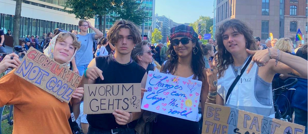 ©2025 Handeln JETZT! Projektgruppe NatureawarnessteamCHVNGE Vier junge Leute sind auf einer Demo mit selbst geschriebenen Demoschildern