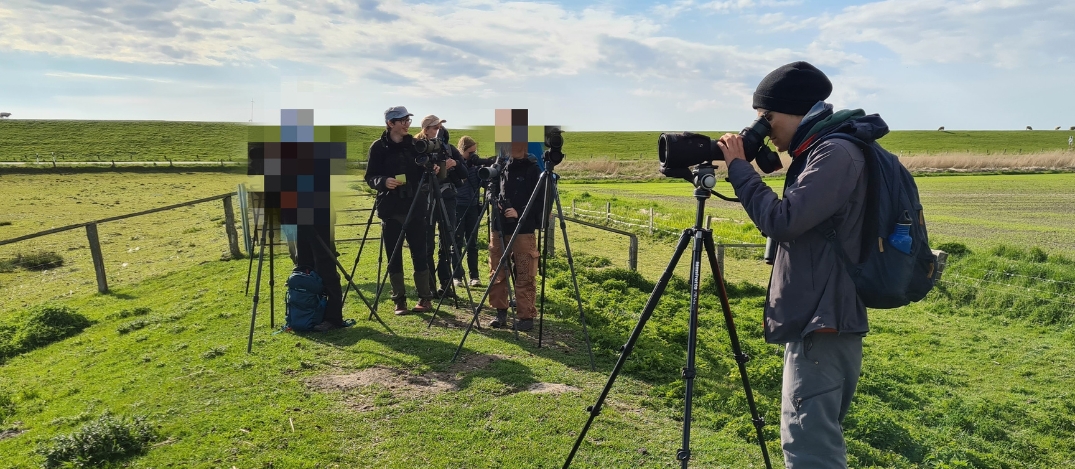 ©2025 Handeln JETZT! Projektgruppe Vogelkiek Gruppe steht im Grünen und guckt durch Beobachtungsgerät